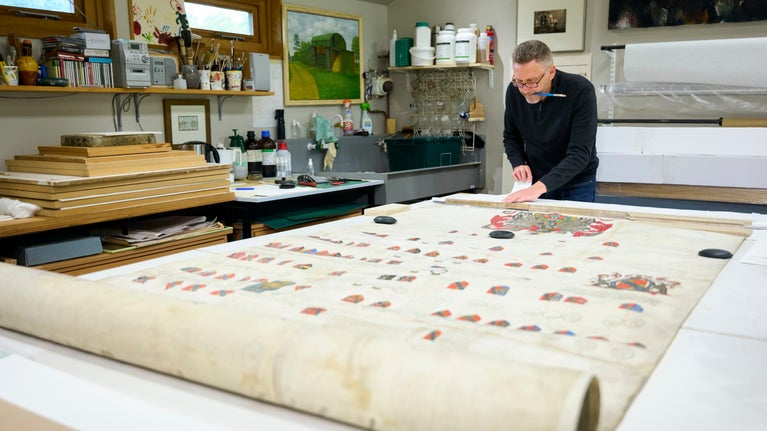 Someone working on the large parchment of the Sackville Family Patents and Pedigrees from Knole at The Studio, Langley Cottage, Cambridgeshire
